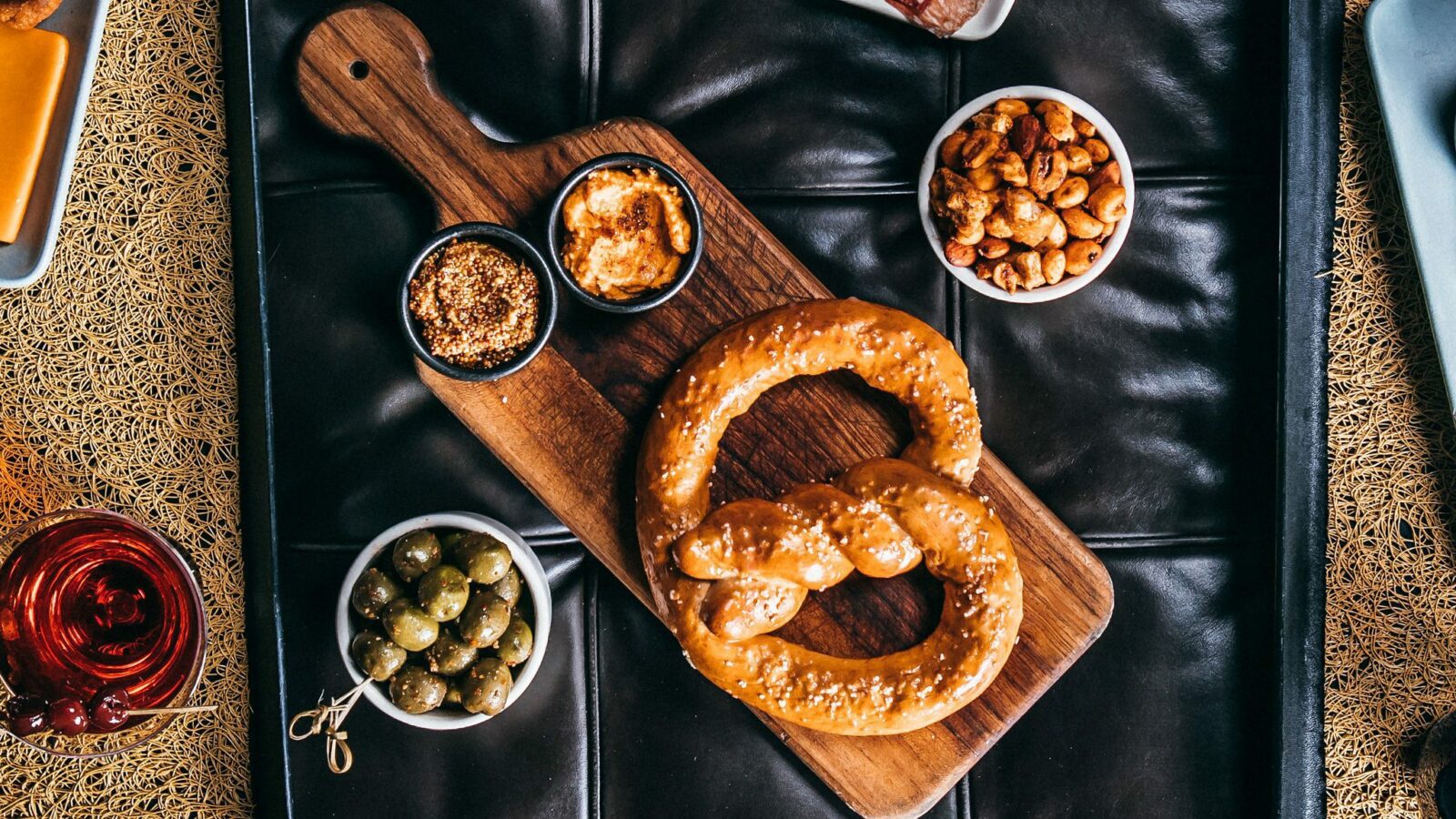 Overhead view of Press pretzel, olives, hummus, cheese, and accompaniments.